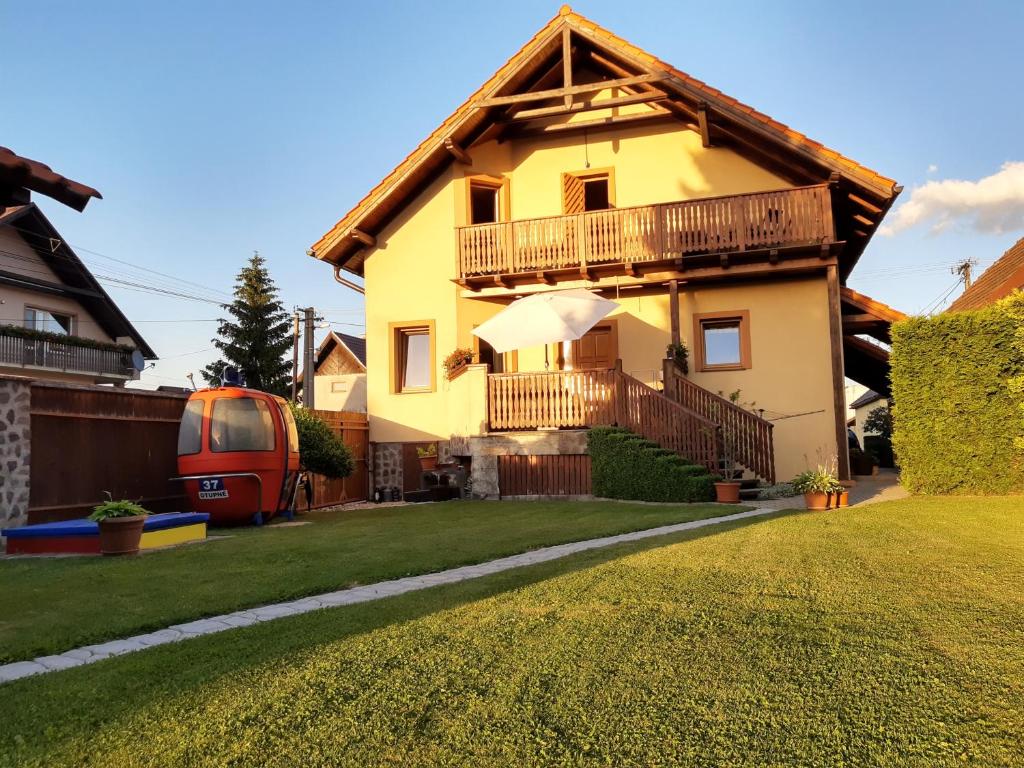 a yellow house with a balcony and a grass yard at Privat Mária in Liptovský Ján