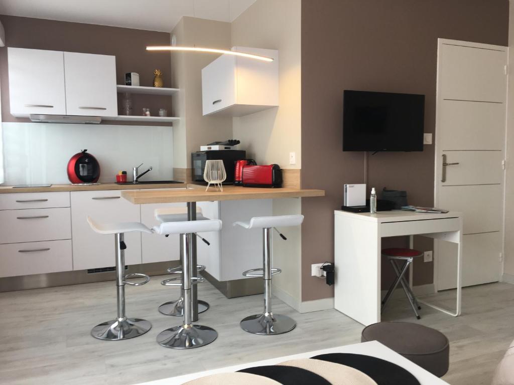 uma cozinha com armários brancos e uma mesa com bancos em Charmant Studio 25 m2, 900m de la plage em Les Sables-dʼOlonne