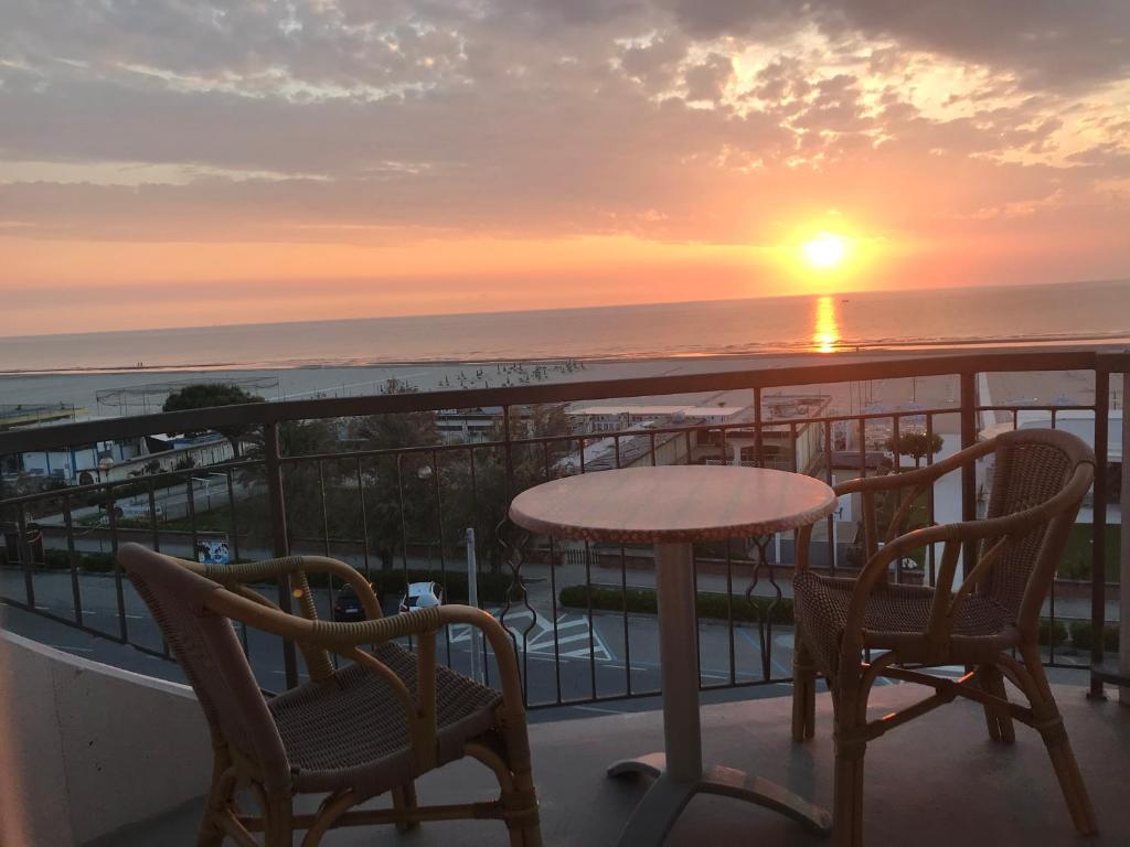 a balcony with a table and chairs and the sunset at Hotel Moderno - Bed & Breakfast in Cervia