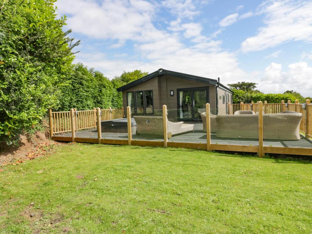 a small house with a deck with a couch and a fence at Pinehurst Lodge in Redruth