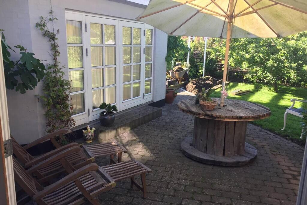 a patio with a table and an umbrella at Charmerende byhus i Præstø centrum in Præstø