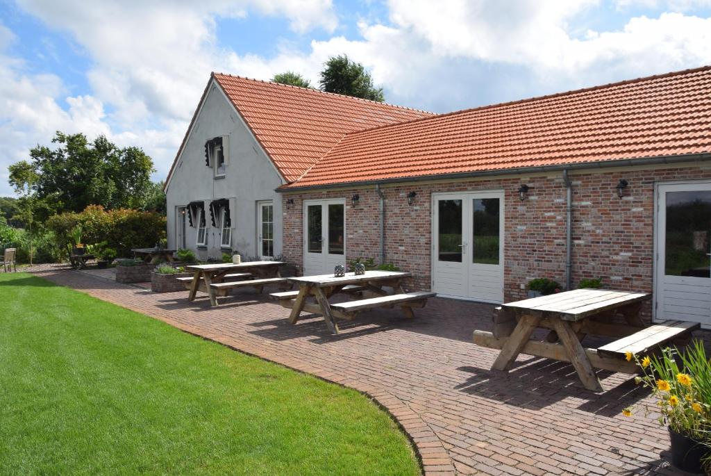 a group of picnic tables in front of a building at Hoeve Delshorst in Heibloem