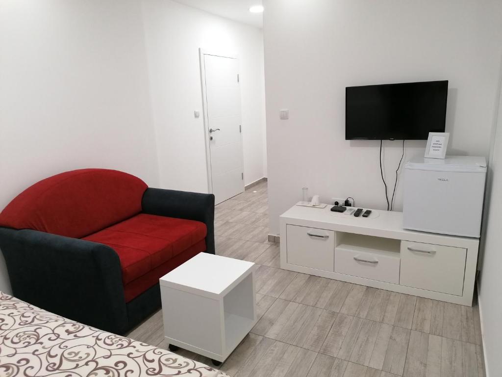 a living room with a red chair and a tv at Airport view Apartment in Belgrade