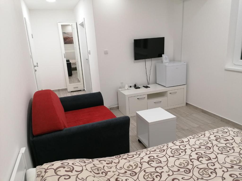 a room with a bed and a chair and a television at Airport view Apartment in Belgrade