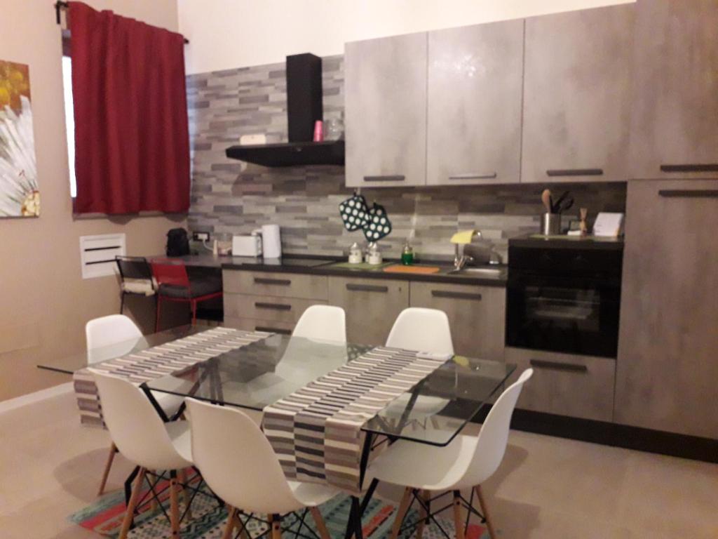 una cucina con tavolo in vetro e sedie bianche di Nuovissimo appartamento lungomare (check out 13:00) a Bari