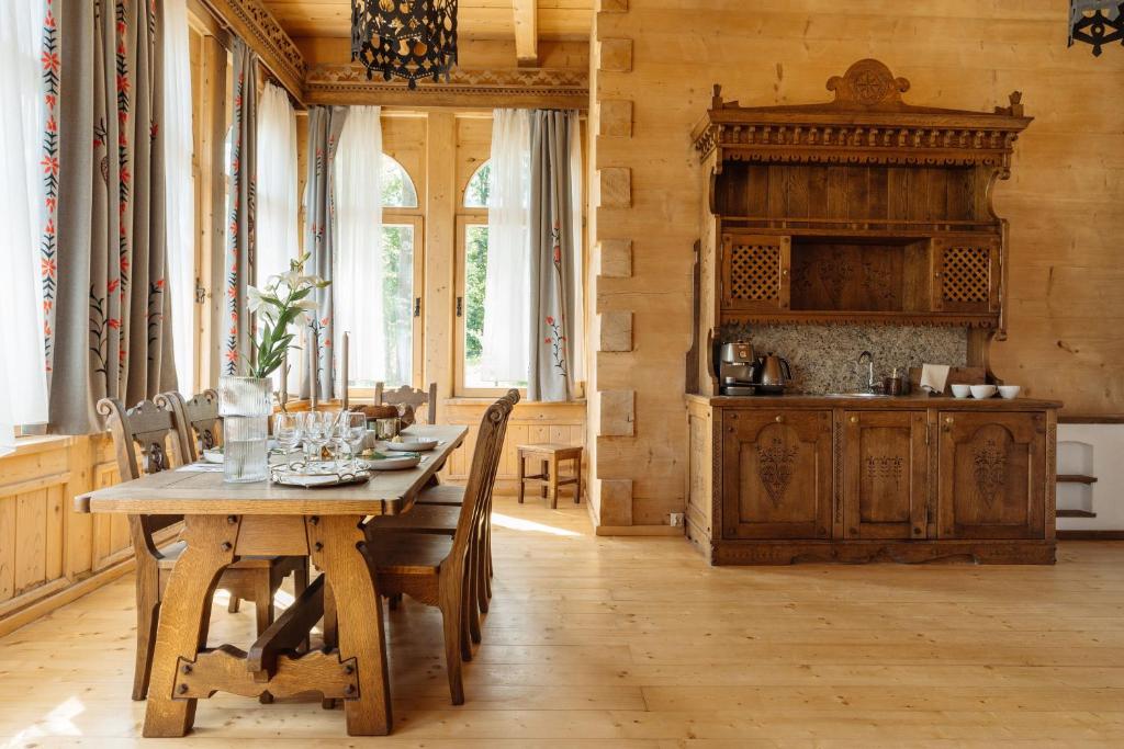 a dining room with a wooden table and a kitchen at Podhalańskie Tarasy - LoftAffair in Kościelisko