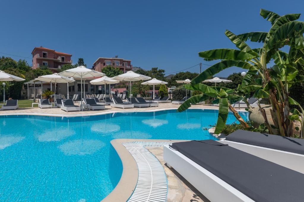 uma grande piscina com espreguiçadeiras e guarda-sóis em Pelagos Apartments em Skála Kefalonias