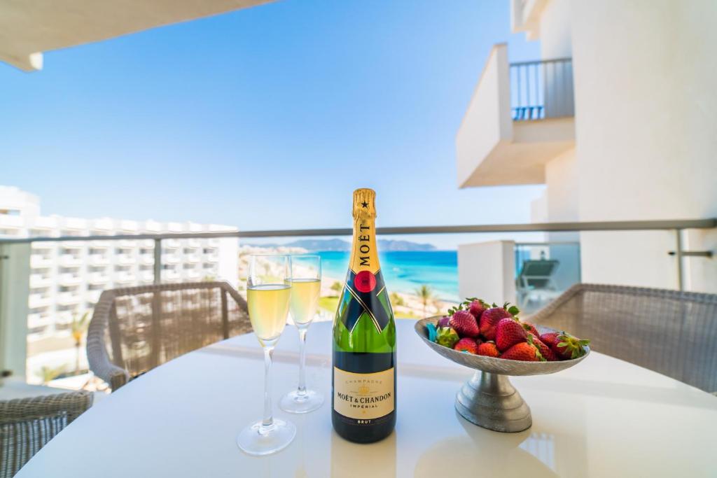 a bottle of champagne and a bowl of fruit on a table at Sa Maniga 6E in Cala Millor