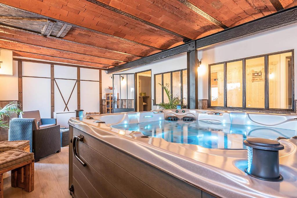 een grote hot tub in een kamer met ramen bij Domaine La Grange Ungersheim - Gîte La Grange 5 étoiles in Ungersheim