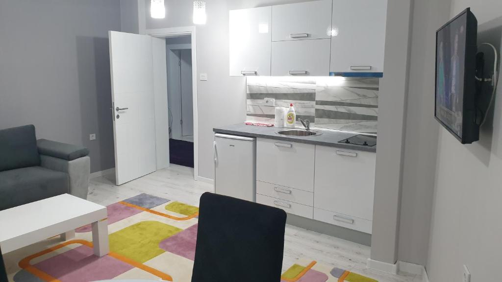 a kitchen with white cabinets and a table and a chair at Apartman Sweet dreams 2 in Niš