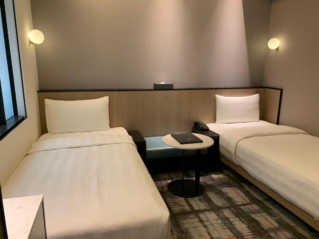 a small room with two beds and a table at Hotel Midtown Richardson in Taipei