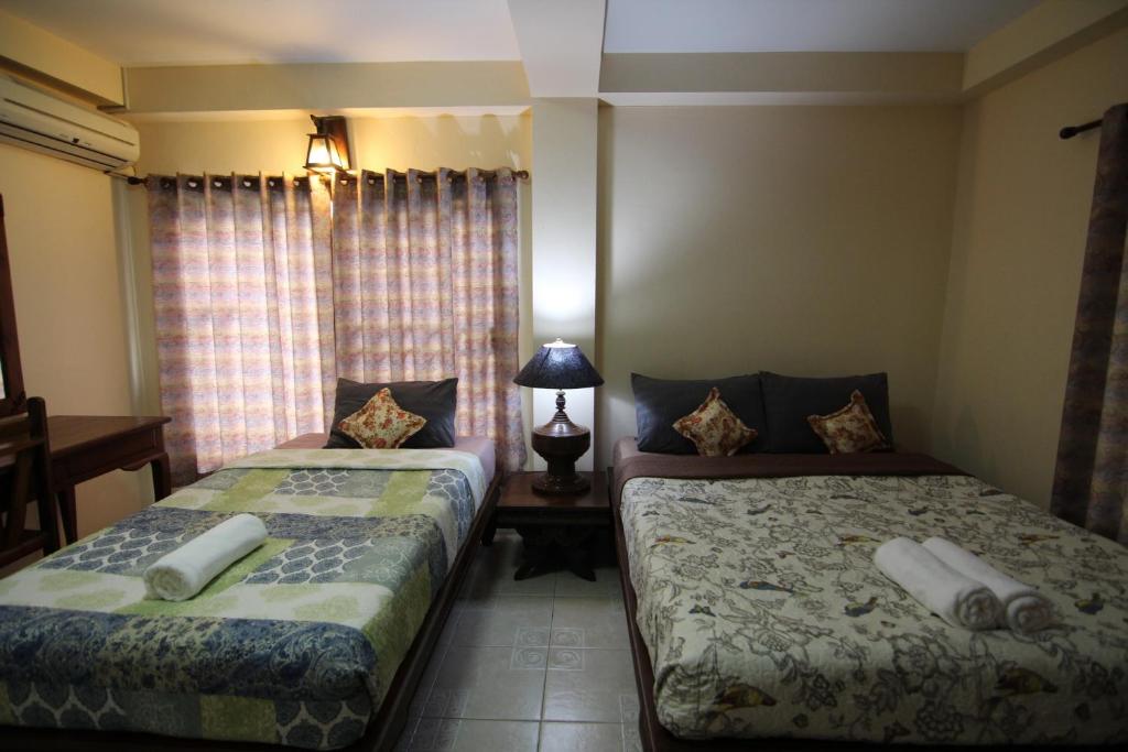 1 dormitorio con 2 camas y mesa con lámpara en S.K.House 2, en Chiang Mai