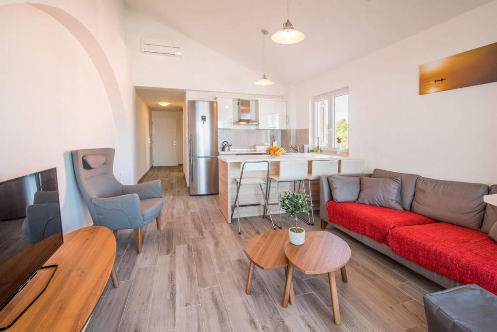 a living room with a red couch and a kitchen at Apartman Zoe Vrbnik in Vrbnik