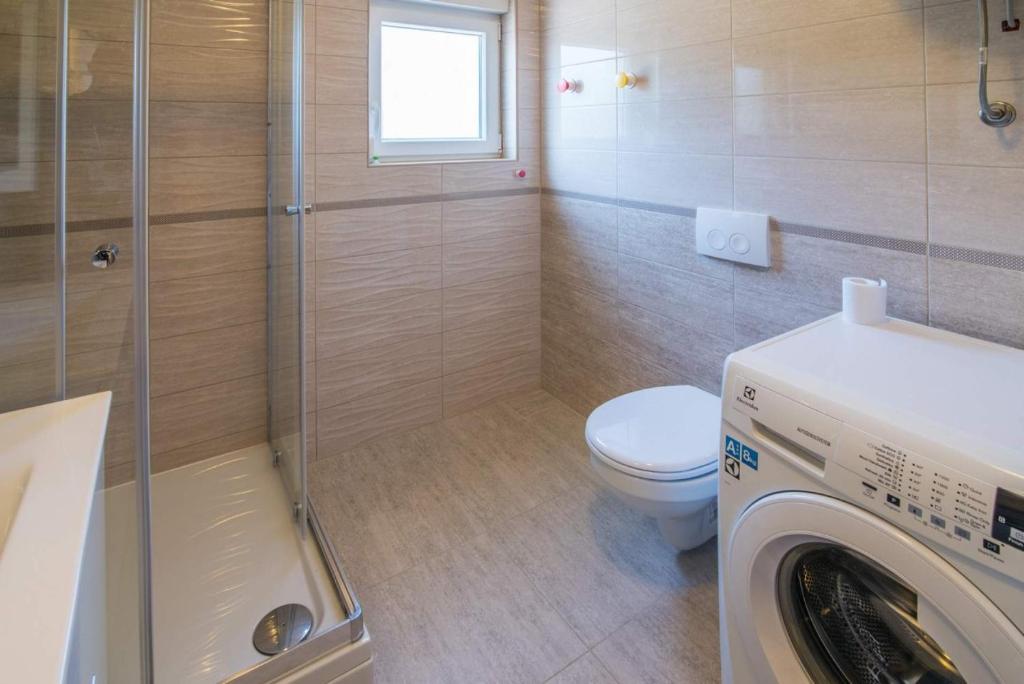 a bathroom with a washing machine and a toilet at Apartman Zoe Vrbnik in Vrbnik