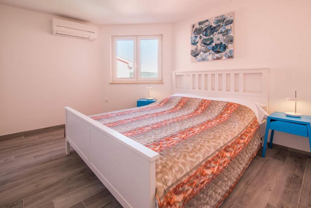 a white bedroom with a large bed and a window at Apartman Zoe Vrbnik in Vrbnik