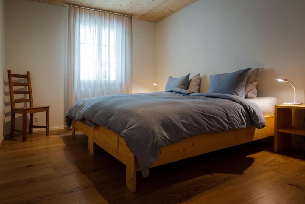 a bedroom with a bed with a blue blanket and a window at B&B Ursi in Andermatt