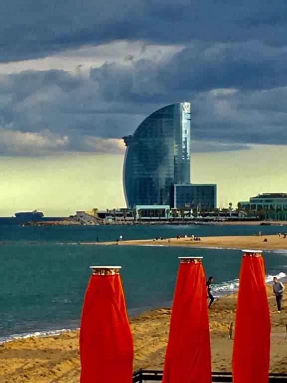 two red umbrellas on a beach with a building at Barceloneta Ramblas Apartments in Barcelona