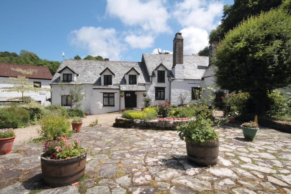 a large white house with potted plants in front of it at Chambercombe Cottages in Ilfracombe