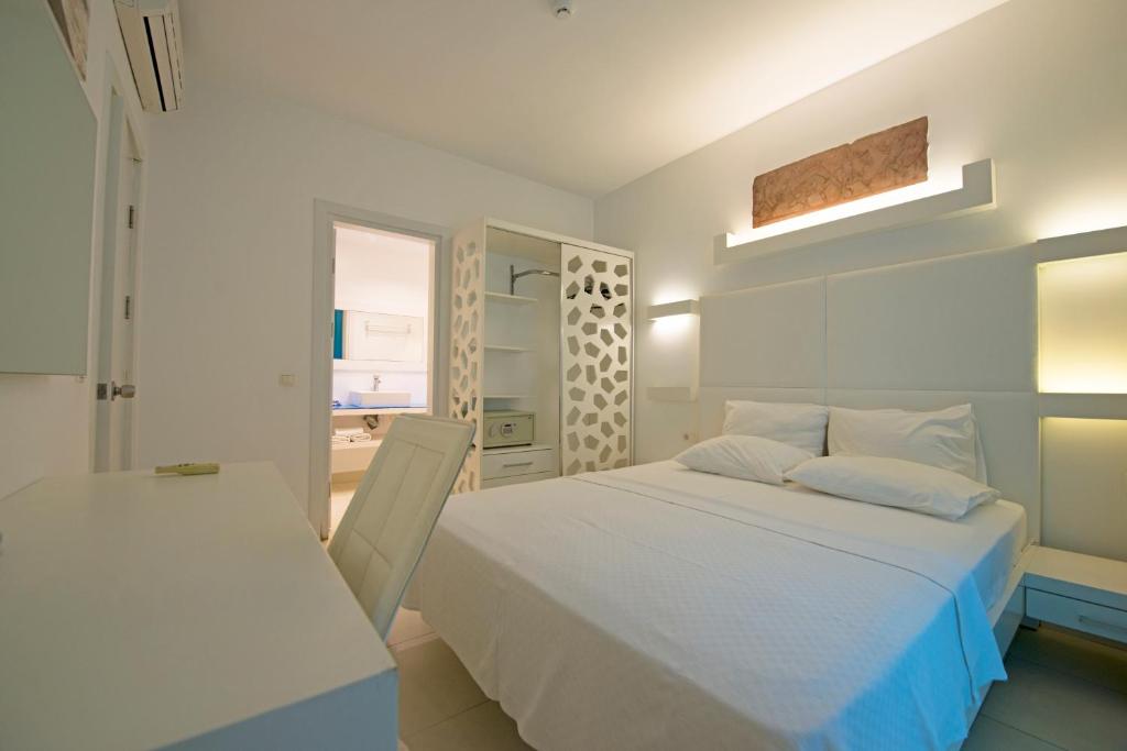 a white bedroom with a bed and a table at Costa Luvi Hotel Bodrum - All Inclusive in Gümbet