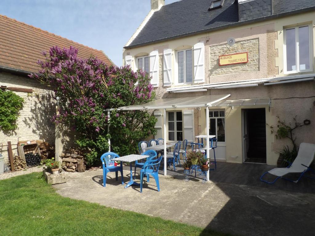 une terrasse avec des chaises bleues et une table en face d'une maison dans l'établissement Chambres et Tables d'hôtes à l'Auberge Touristique, à Meuvaines