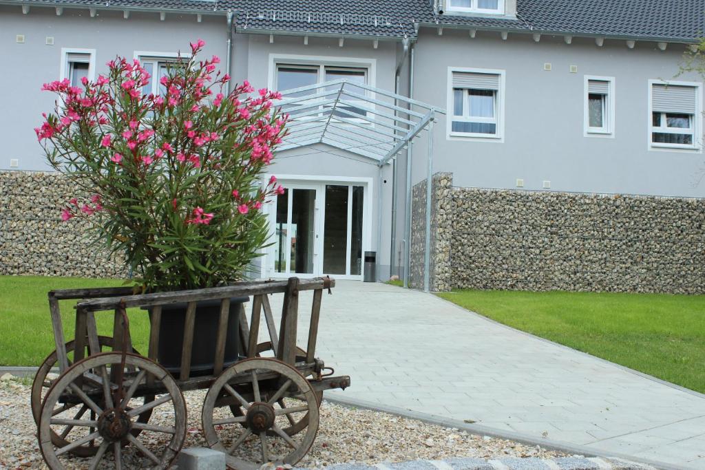 a plant in a wooden cart in front of a house at Hotel Alex in Stammham
