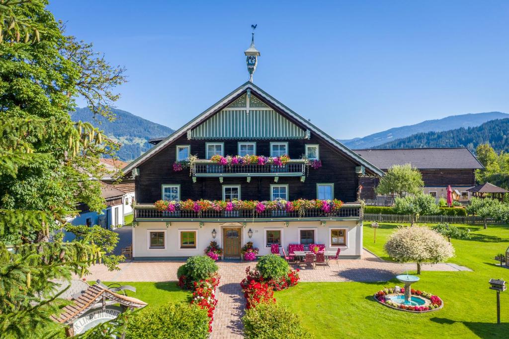 une maison avec un jardin fleuri devant elle dans l'établissement Frühstückspension Klinglhub, à Flachau