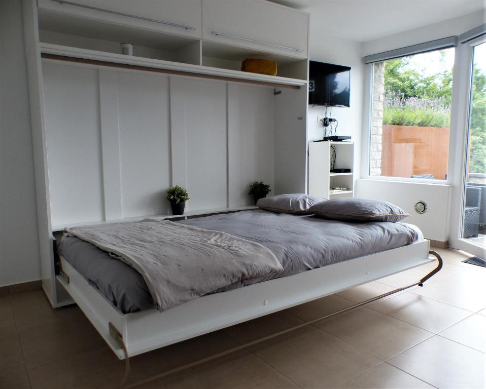 a bedroom with a large bed with white walls at Les terrasses de Malmedy Studio 333 Yellow Grey in Malmedy