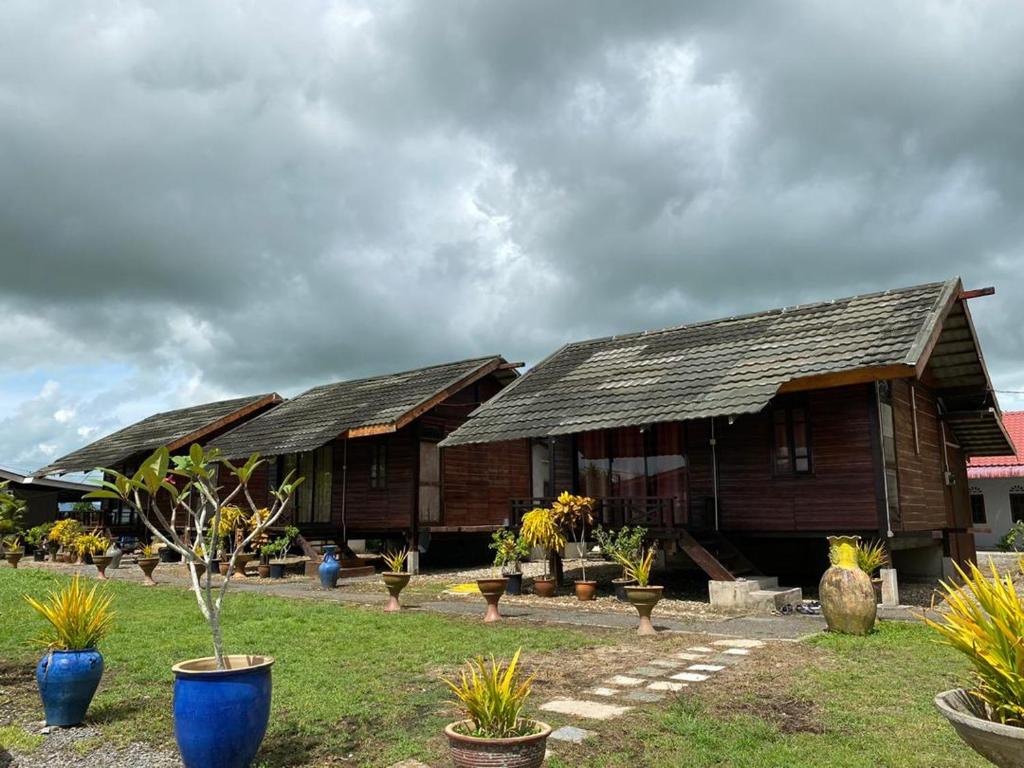 two wooden buildings with plants in front of them at Tamteh Homestay in Ayer Hitam