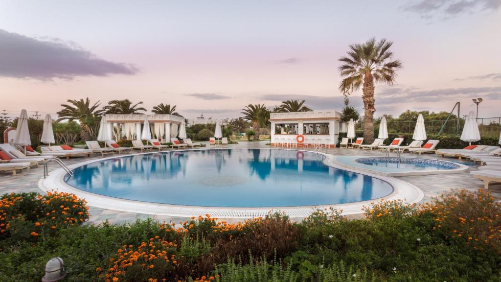 een groot zwembad met stoelen en palmbomen bij Porto Naxos in Naxos Chora