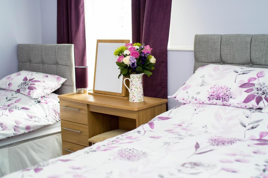 a bedroom with a bed and a mirror and a vase of flowers at Aden House Bed And Breakfast in Mintlaw