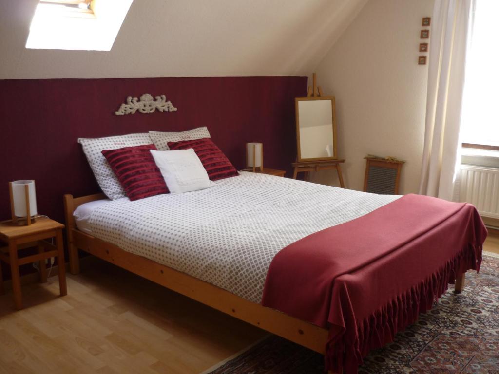 a bedroom with a large bed with red and white pillows at Les Pensées in Braine-lʼAlleud