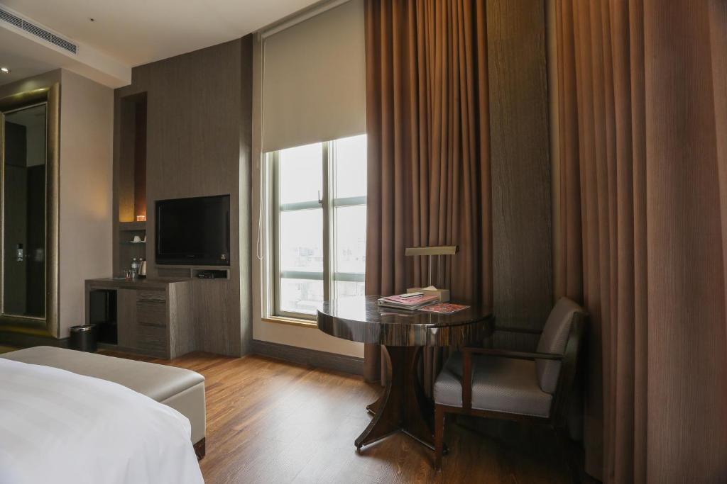 a hotel room with a bed and a desk and a window at City Suites - Taipei Nandong in Taipei