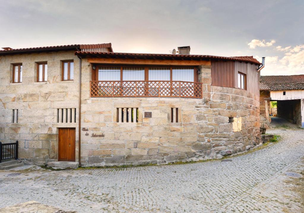 een stenen huis met een houten deur en een balkon bij Casa Da Laborada in Vilar de Perdizes