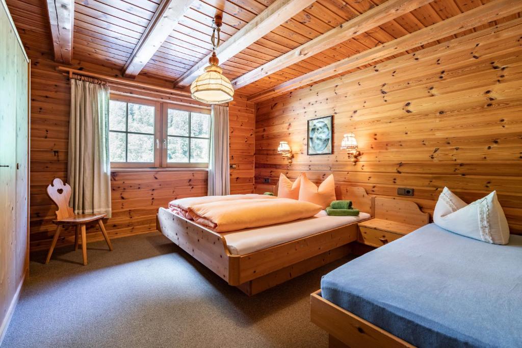 マイヤーホーフェンにあるGasthaus Häusling Almのログキャビン内のベッドルーム1室(ベッド2台付)