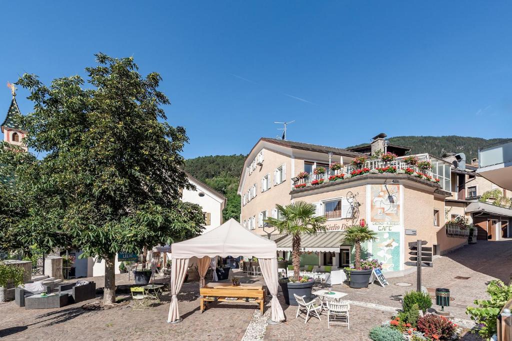 a building with a table and a white umbrella at Hotel Weisse Lilie - Giglio Bianco in Mühlbach