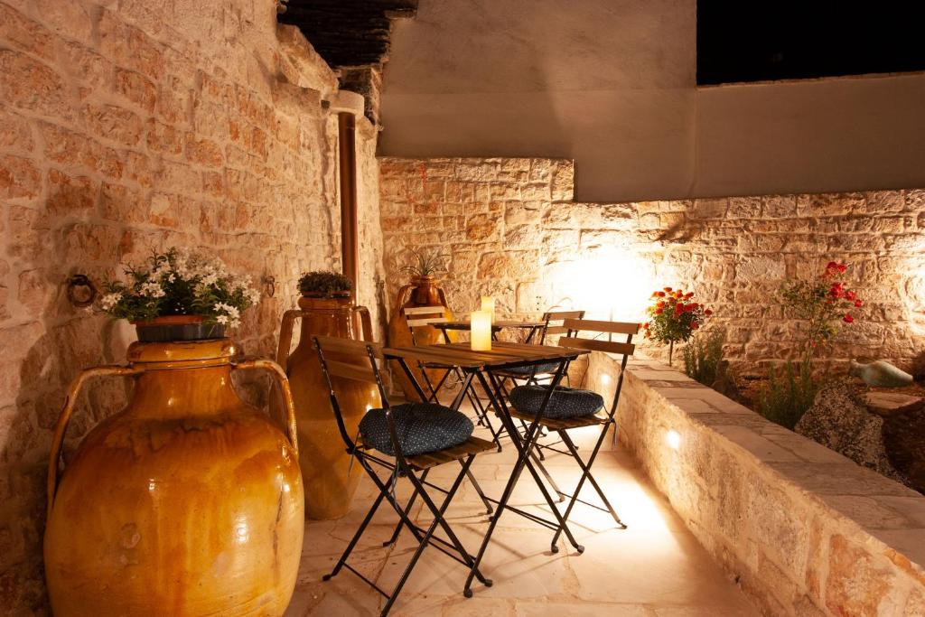 a room with a table and chairs and a stone wall at Trullo Aprìco in Alberobello