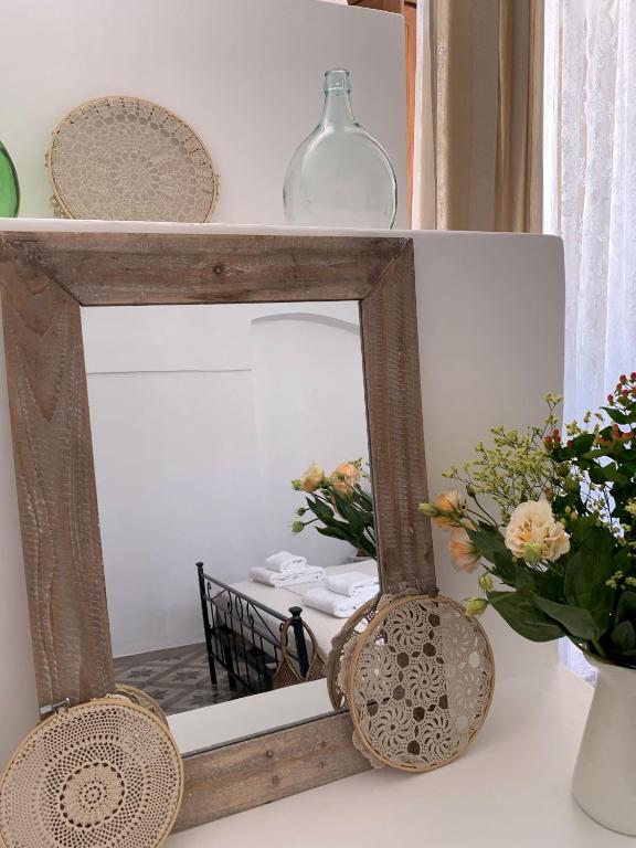 a mirror on a shelf with flowers and a vase at Trullo Aprìco in Alberobello