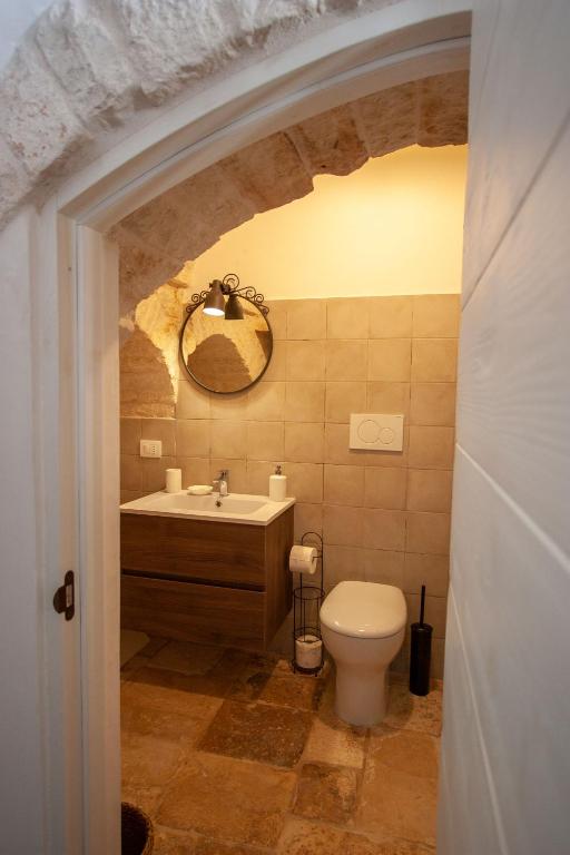 a bathroom with a toilet and a sink and a mirror at Trullo Aprìco in Alberobello