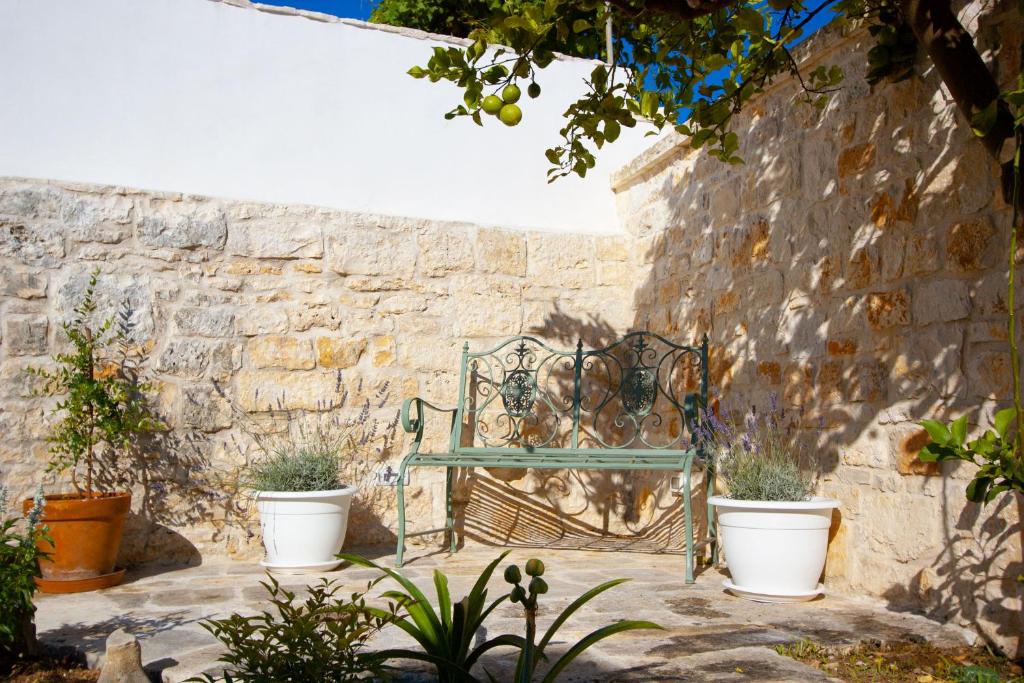 a stone wall with two potted plants in front of a bench at Trullo Aprìco in Alberobello