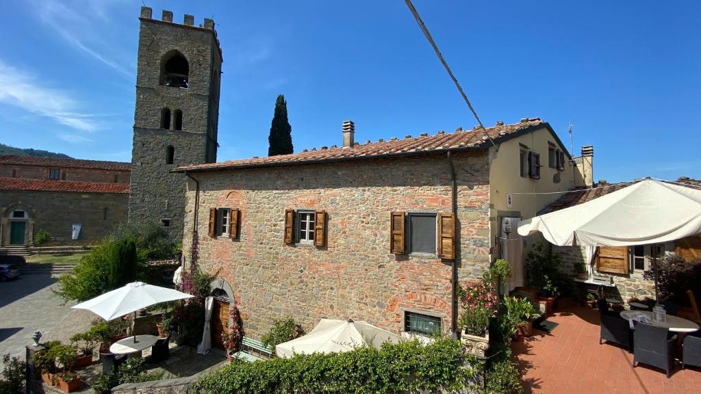 un edificio con mesas, sombrillas y una torre en La Magione dei Todaro, en Borgo a Buggiano