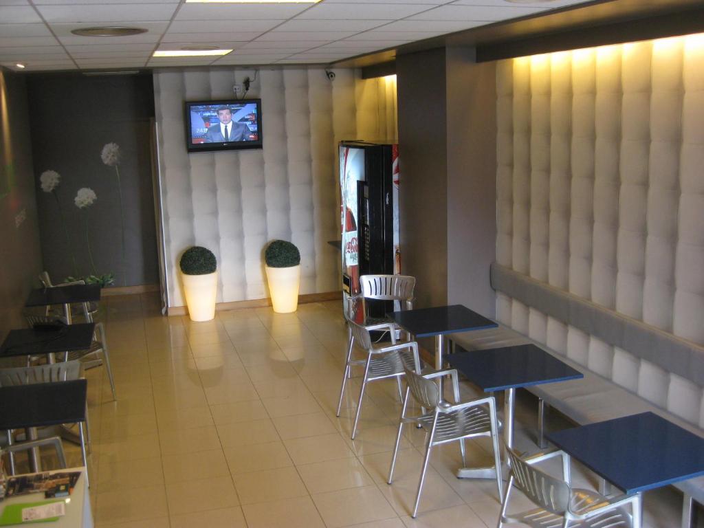 comedor con mesas y sillas y TV en albergue SANTO SANTIAGO, en Santiago de Compostela