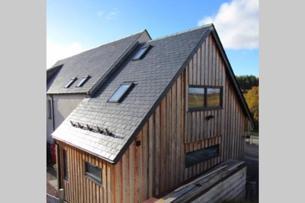 uma casa de madeira com um telhado de gambrel em Drovers Studio Apartment em Tomatin