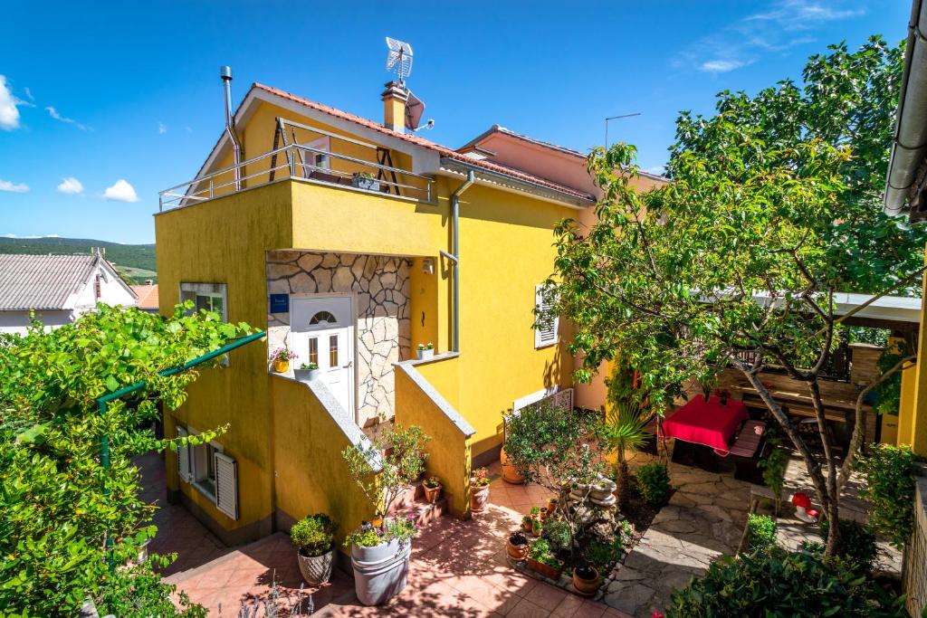 a yellow house with a balcony in a yard at Apartmani Grguric in Kornić