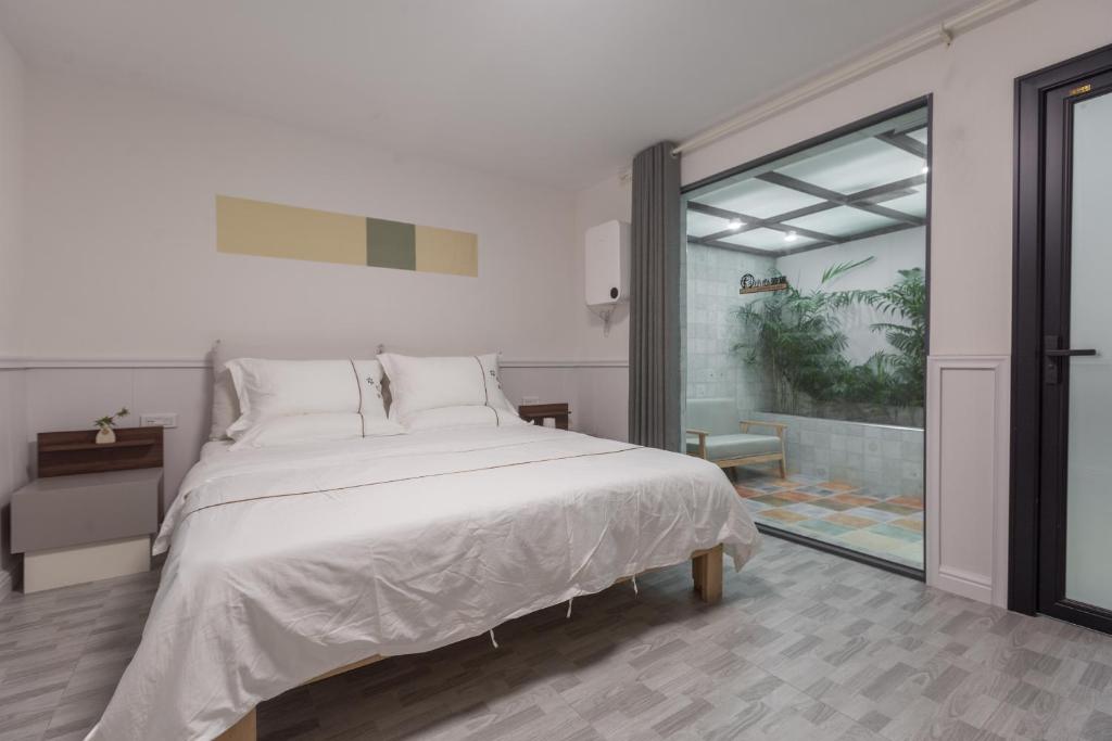 - une chambre avec un lit blanc et une grande fenêtre dans l'établissement Guilin Flowers Inn, à Guilin