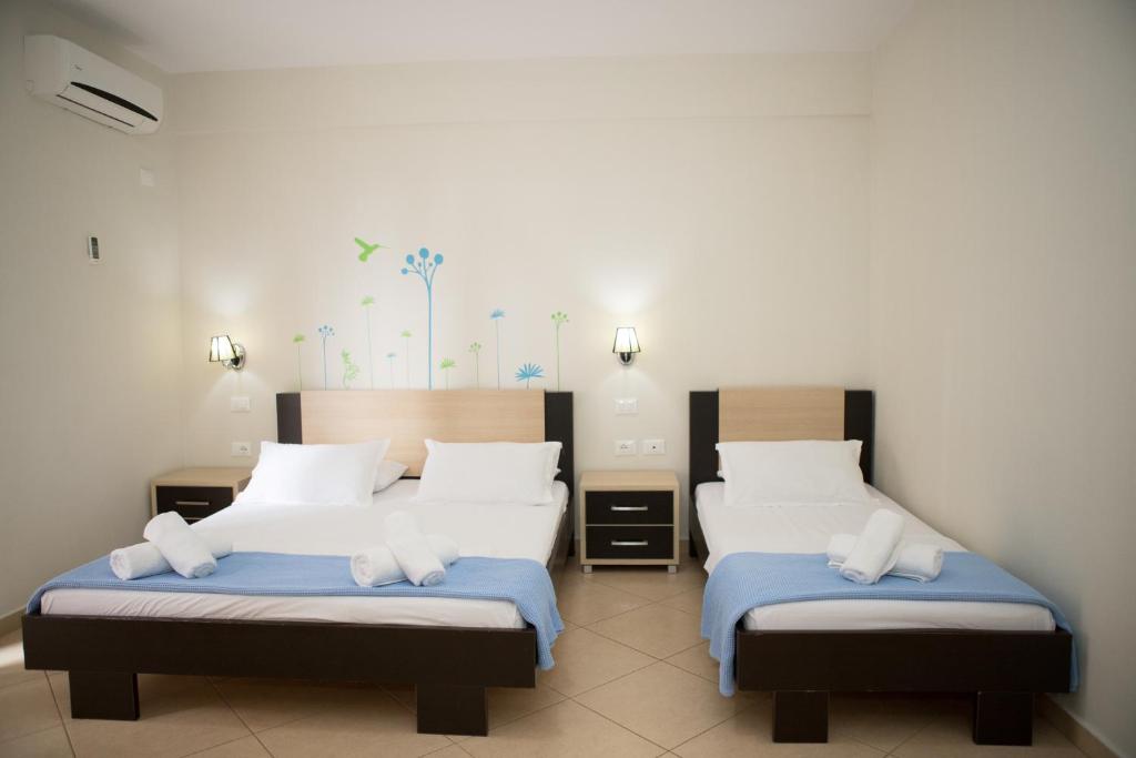a bedroom with two beds with blue sheets at Perivolos Apartments in Dhërmi