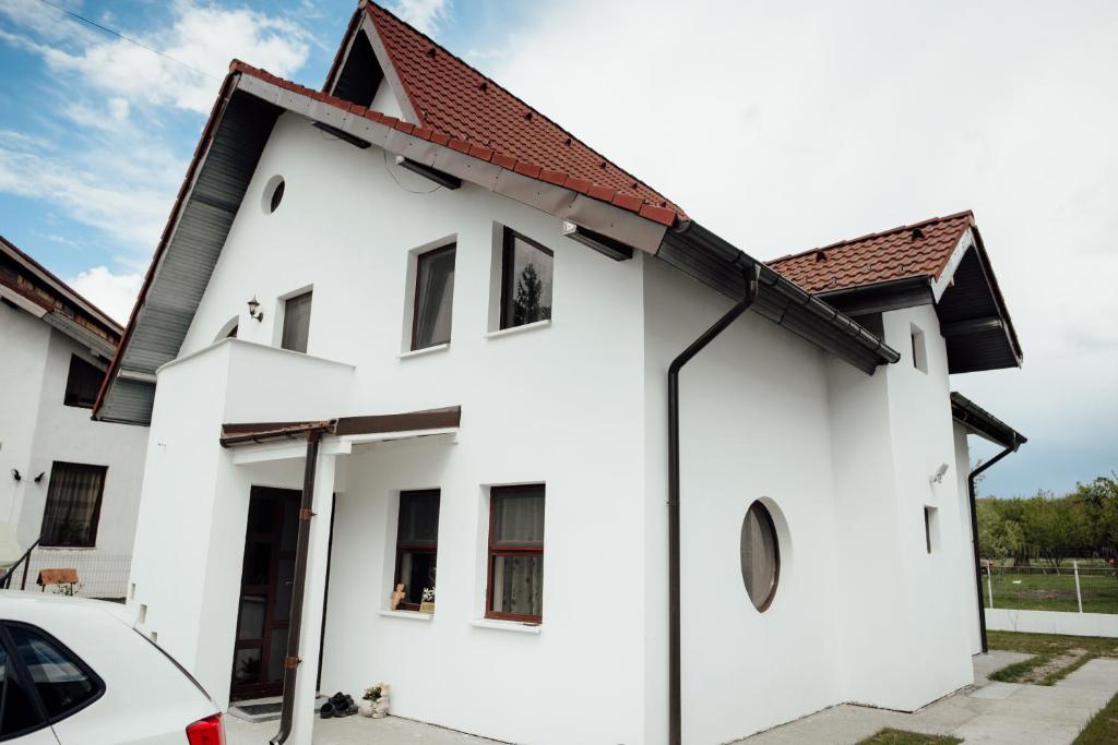 a white house with a red roof at Autentic Adorabil Apartment in Albeştii Pămînteni
