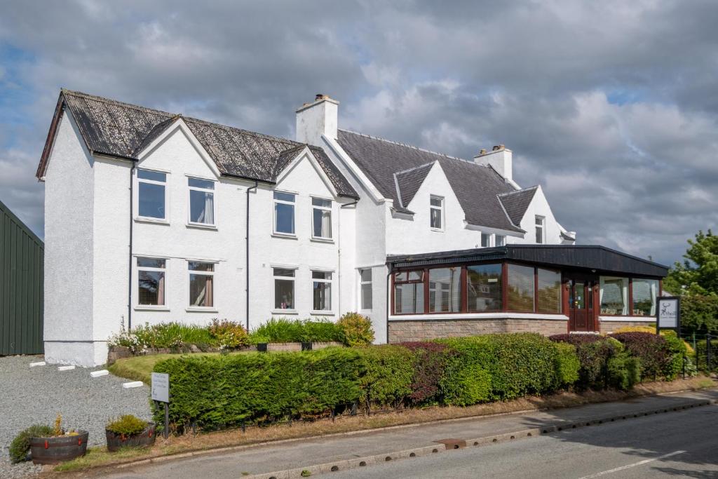 een wit huis met een zwart dak bij Atholl House Skye in Dunvegan