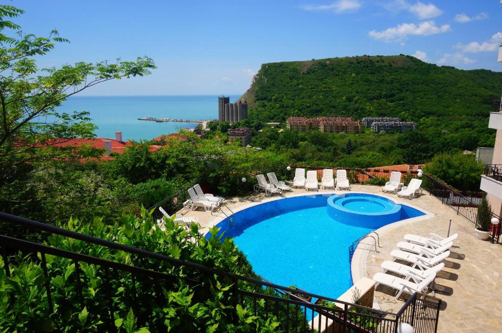a swimming pool with chairs and a view of the ocean at Апартаменти Свети Георги - Saint George Apartments in Kavarna