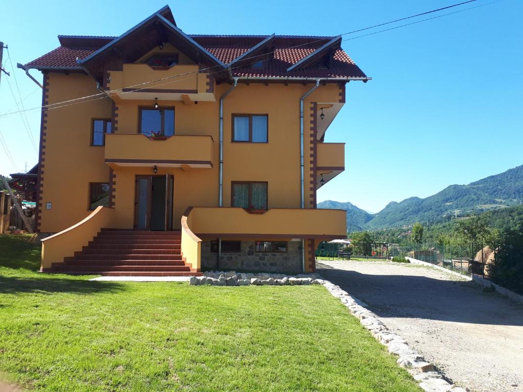 a large yellow house with stairs and grass at Pensiunea Annalisa in Corbeni