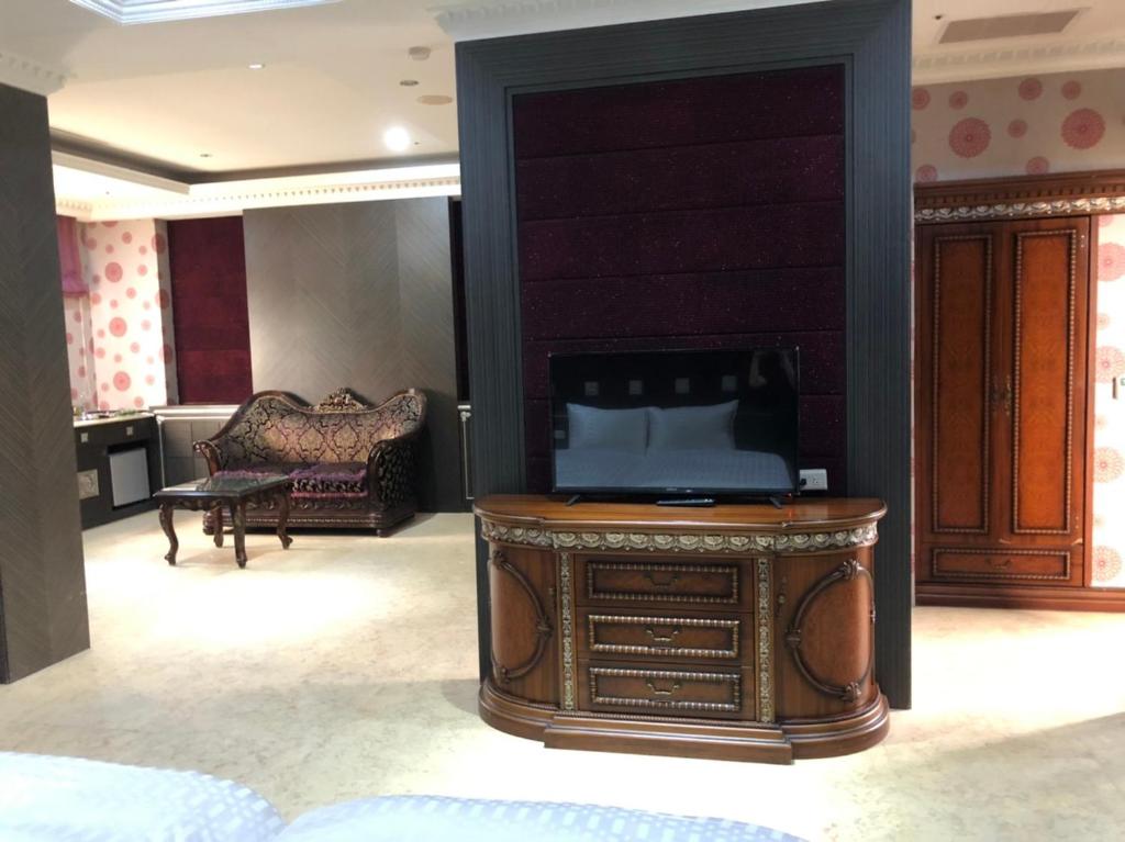 - un salon avec une télévision et un canapé dans l'établissement Royal Garden Motel - Chiayi Branch, à Chiayi